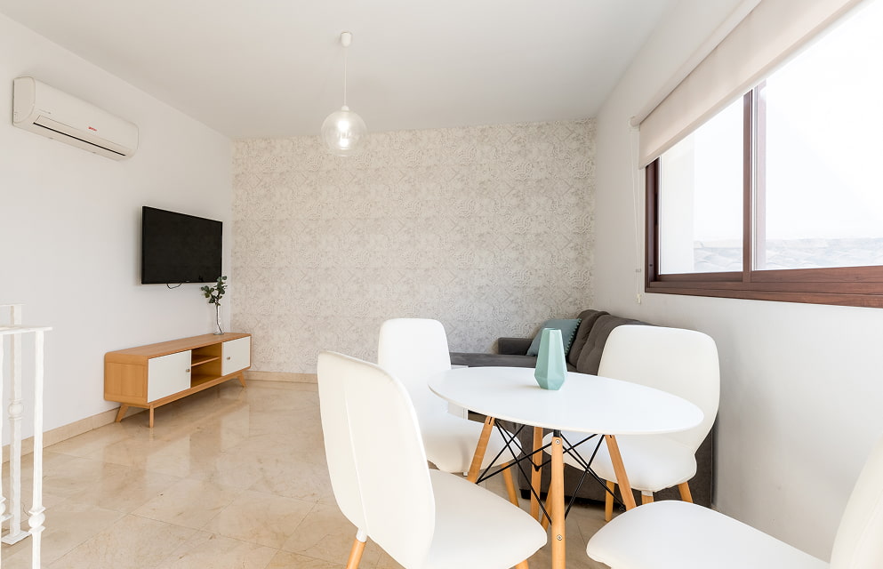 Sala de Estar Sala de estar de uno de los apartamentos de Hoteles del Sur, con TV, aire acondicionado, sofá y juego de mesas con silla